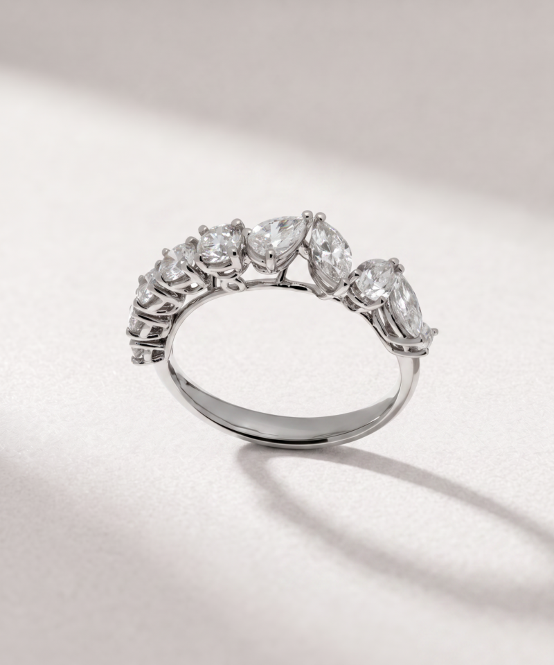 Side profile of a K18 white gold ring set with pear-shaped and round diamonds