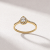Front view of a K14 yellow gold ring with a pear-cut center diamond and surrounding diamond halo