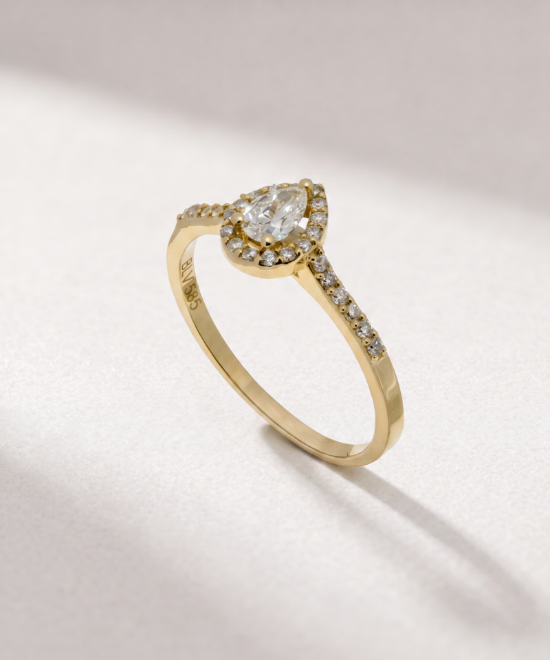 Angled view of a pear-cut diamond halo ring in K14 yellow gold