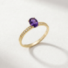 Angled view of an oval-cut amethyst and zirconia ring in K14 yellow gold
