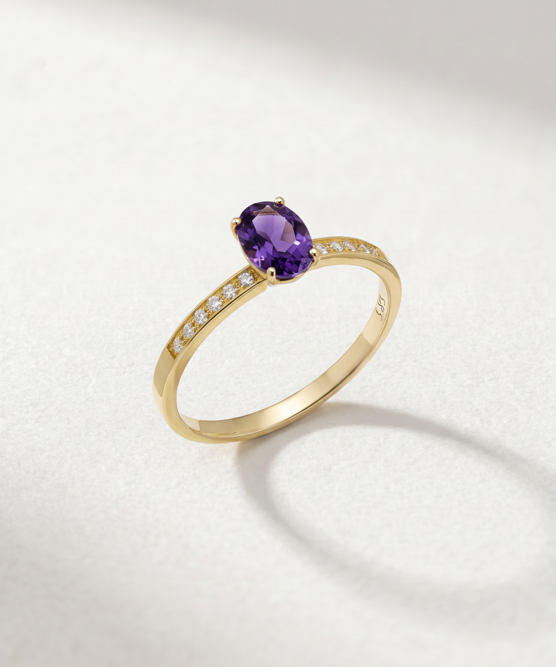 Angled view of an oval-cut amethyst and zirconia ring in K14 yellow gold