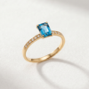 Emerald-cut blue topaz ring in K14 yellow gold with stone-set shoulders