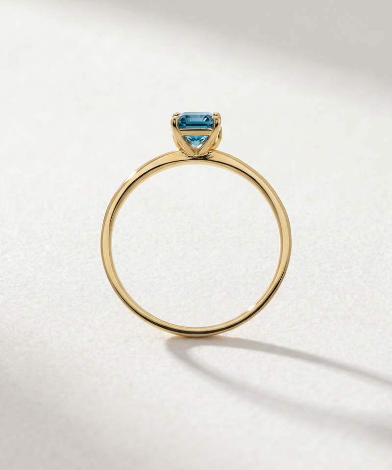 Emerald-cut blue topaz ring in K14 yellow gold with stone-set shoulders