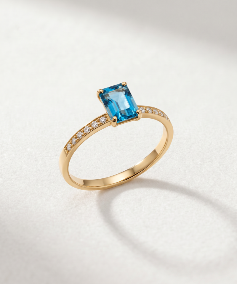 Emerald-cut blue topaz ring in K14 yellow gold with stone-set shoulders
