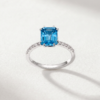 K18 white gold ring featuring a rectangular blue topaz centre stone with diamonds along the band.