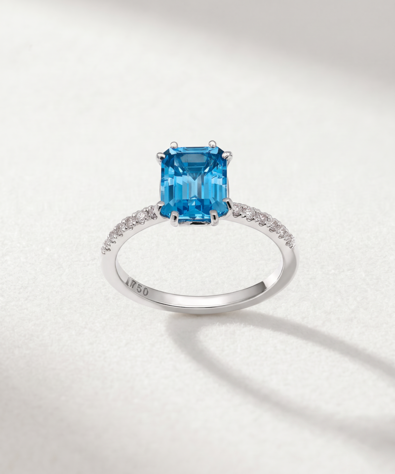 K18 white gold ring featuring a rectangular blue topaz centre stone with diamonds along the band.